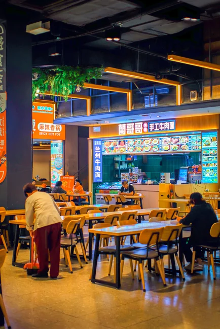 Side view of young ethnic male in uniform cleaning floor with mop while working in retro styled restaurant